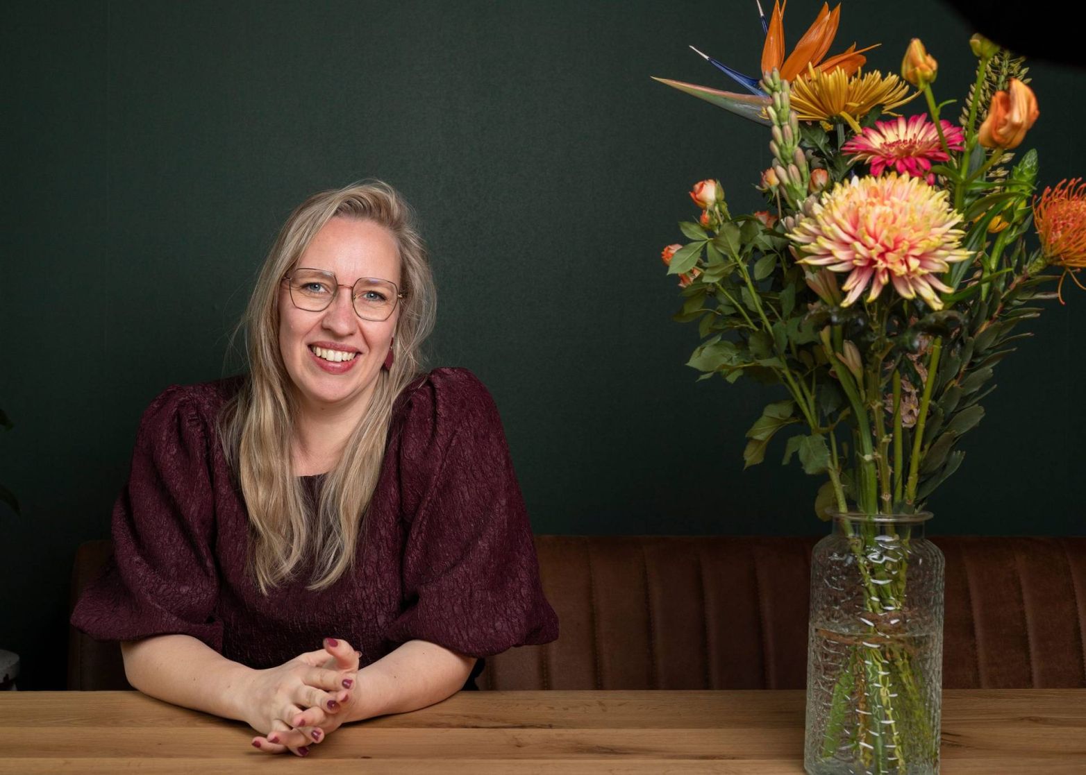 Maxime Chloë de Vos, zorgconsultant, aan tafel met een bos bloemen